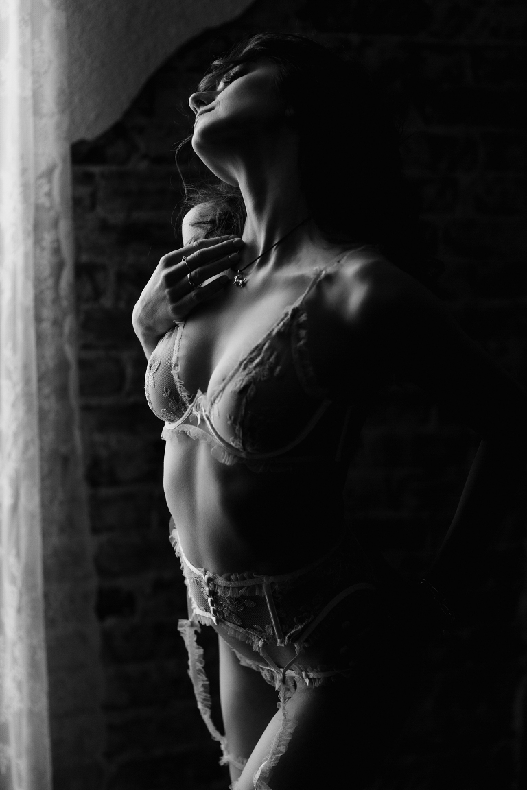 Denver boudoir photography client posing with brick background